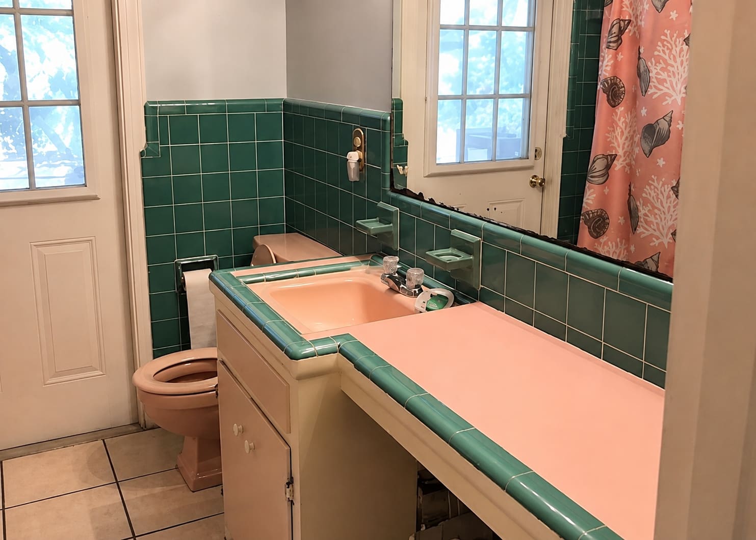 Bathroom before remodel — dated green tile and pink fixtures