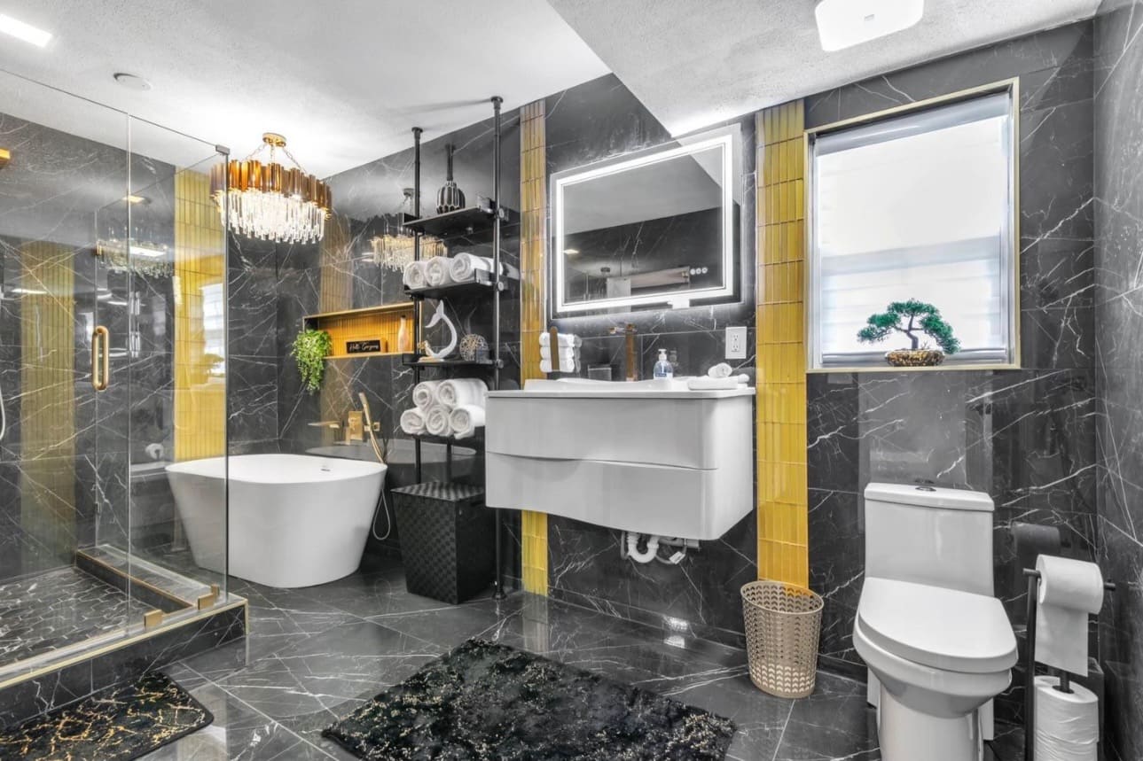 Finished luxury bathroom remodel with black marble tile, freestanding tub and glass shower — REV Home Solutions