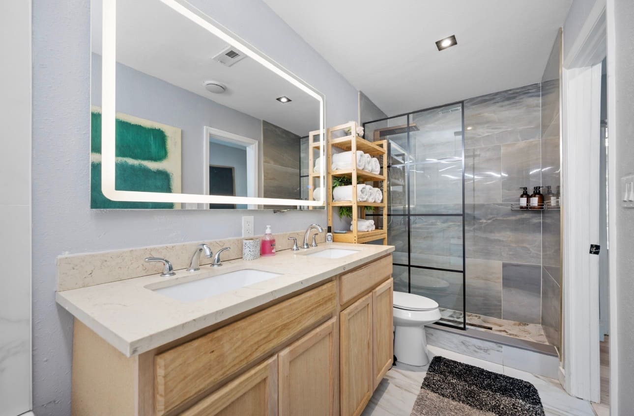 Finished bathroom remodel with wood vanity and glass shower — REV Home Solutions
