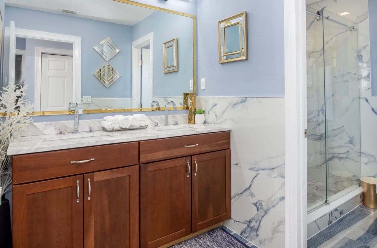 Finished bathroom remodel with wood vanity and marble tile — REV Home Solutions