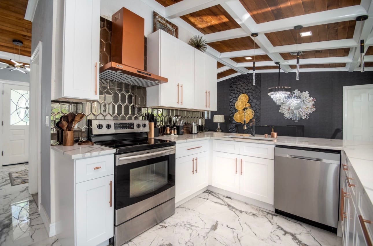 Finished kitchen with copper range hood and mirrored tile backsplash, part of a full home renovation — REV Home Solutions
