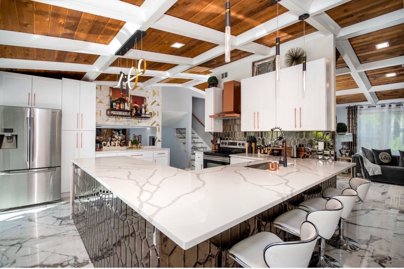 Finished full home renovation — open-concept kitchen with mirrored tile bar, stairs and living room beyond