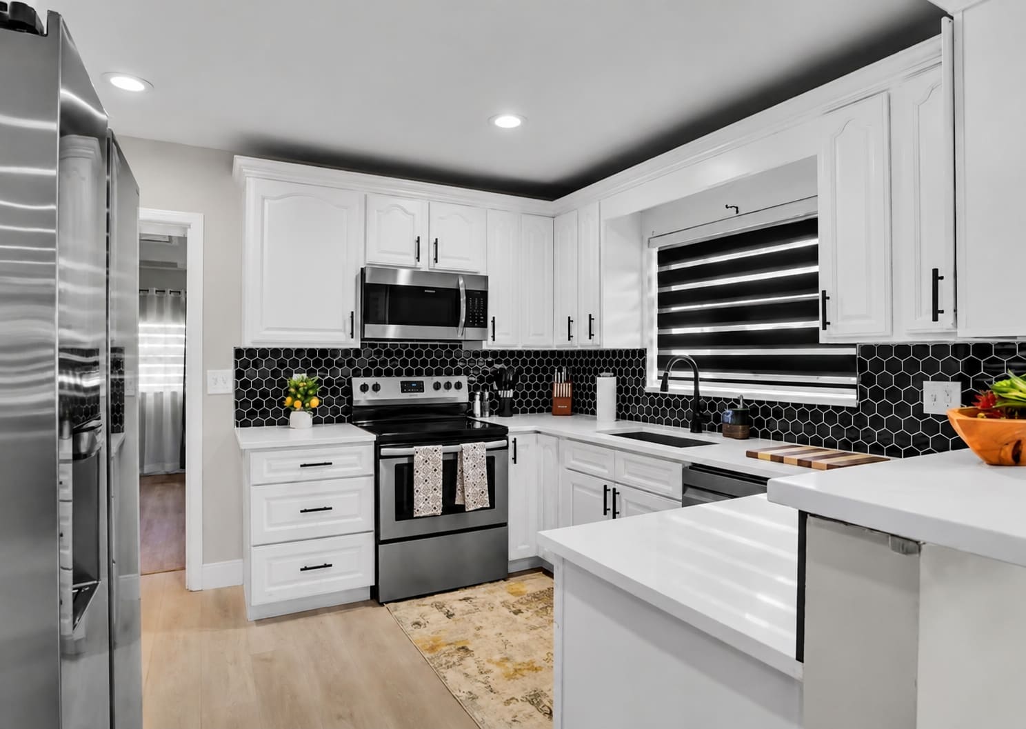 Finished kitchen remodel with white cabinetry and black hexagon tile backsplash — REV Home Solutions
