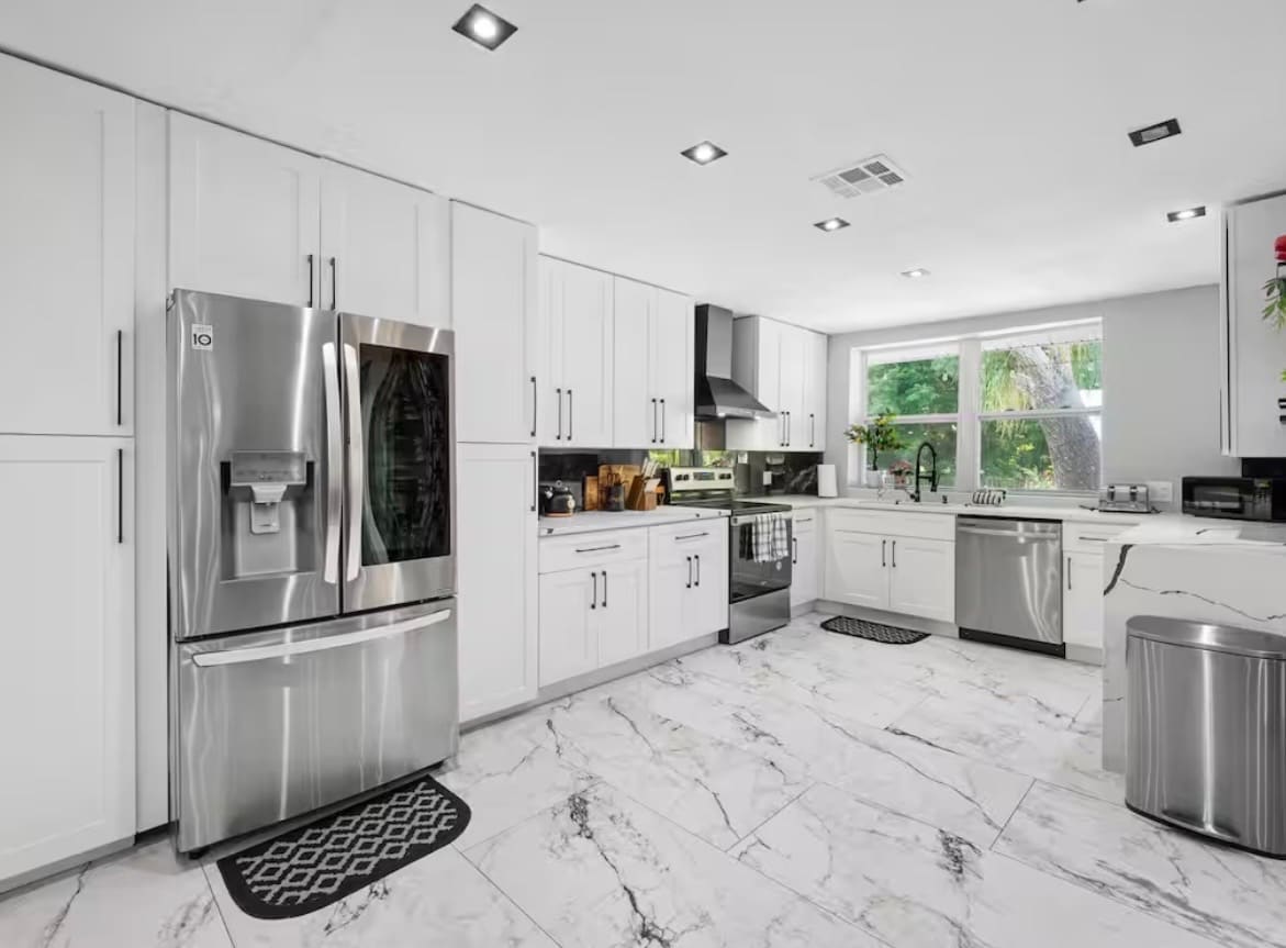Finished kitchen remodel with white cabinetry and black marble-look backsplash — REV Home Solutions