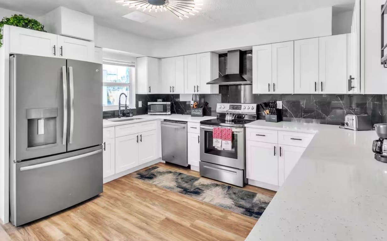Finished kitchen remodel with white cabinetry and stainless steel appliances — REV Home Solutions