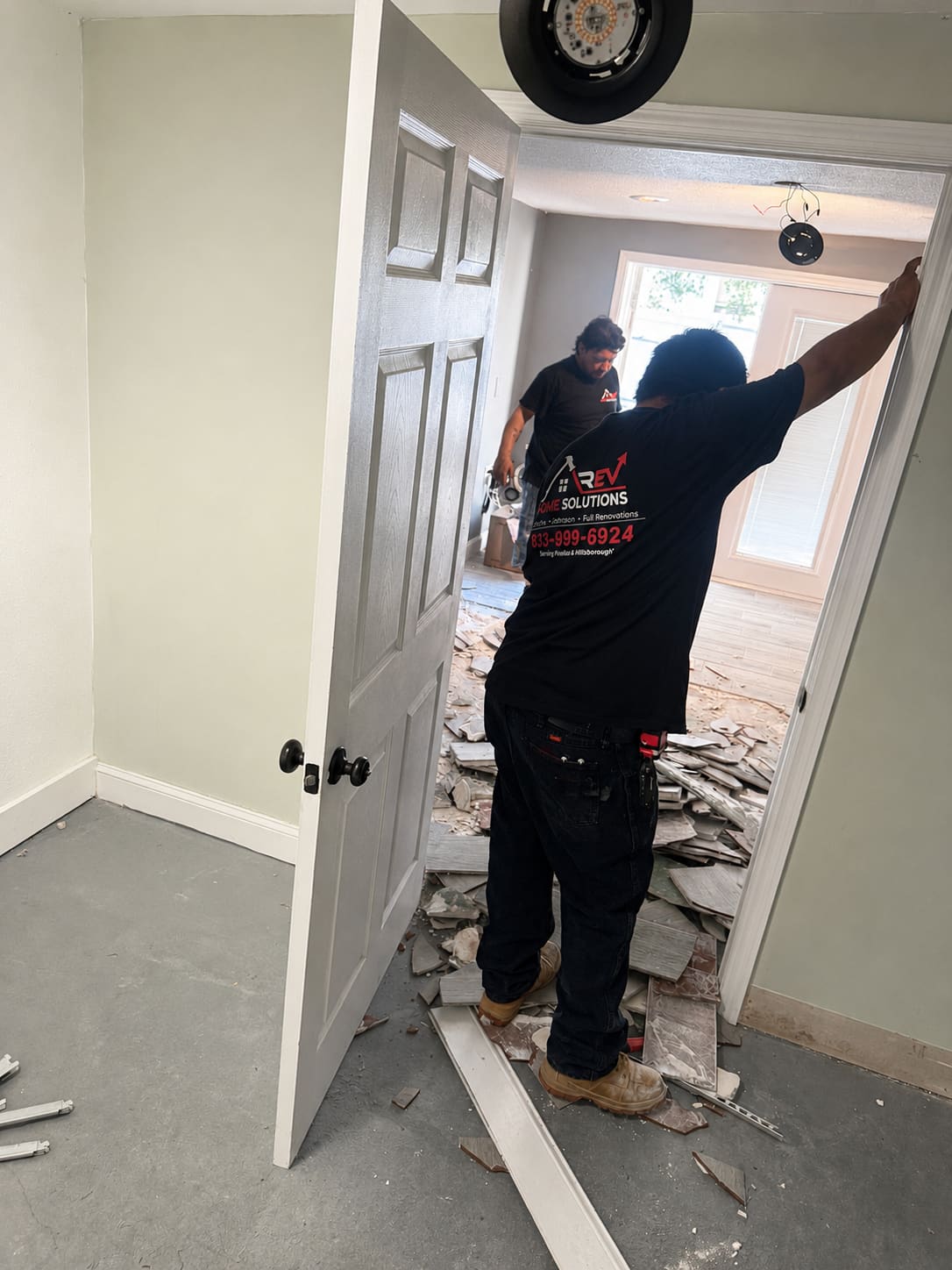 REV Home Solutions crew removing tile flooring during a full home renovation