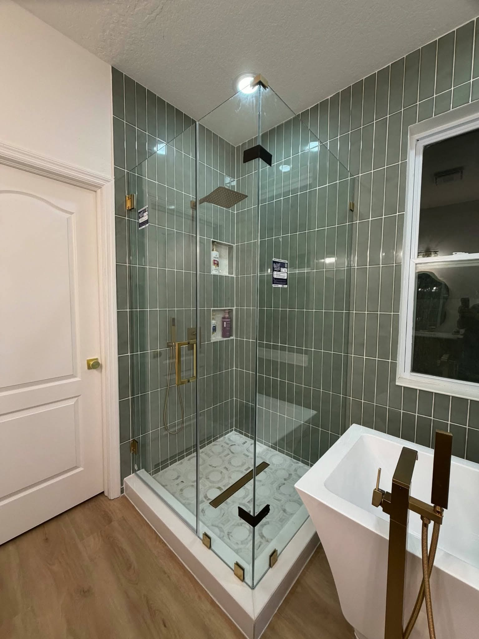 Finished corner shower with sage green vertical tile and gold fixtures — REV Home Solutions