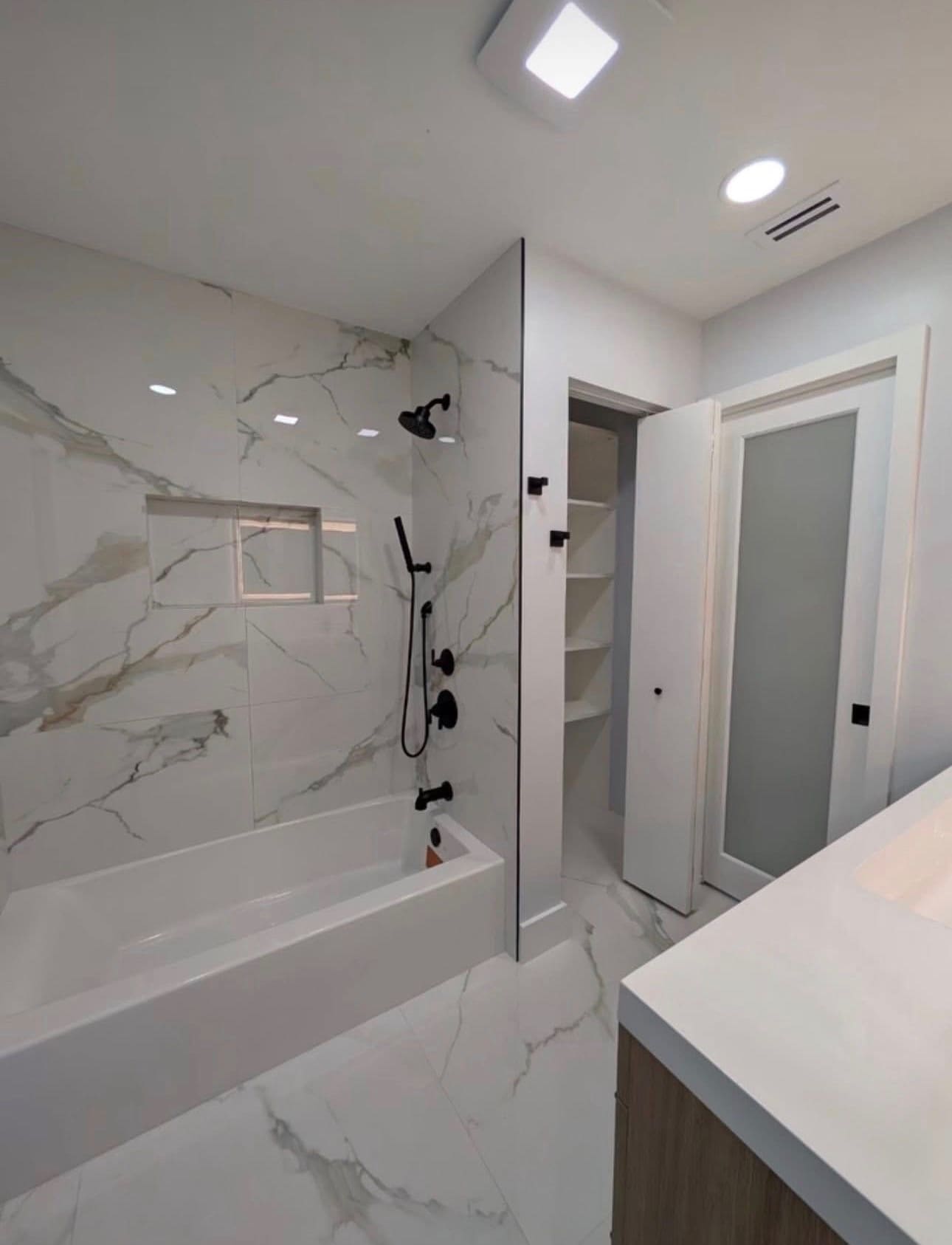 Finished tub/shower combo with marble-look tile and matte black fixtures — REV Home Solutions