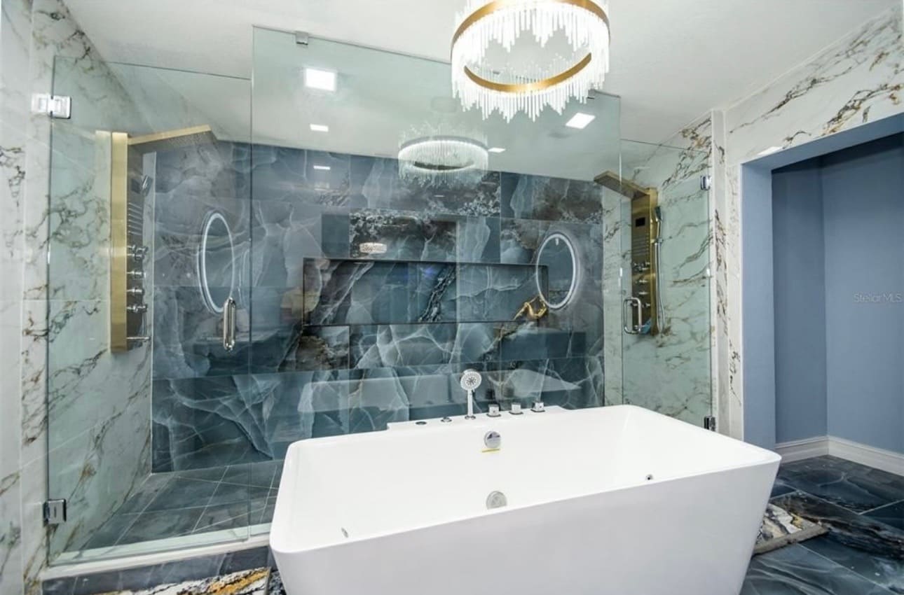 Finished walk-in shower with dramatic dark stone tile, gold fixtures and freestanding tub — REV Home Solutions